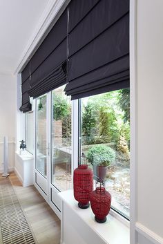 two red vases sitting on top of a window sill next to a white wall