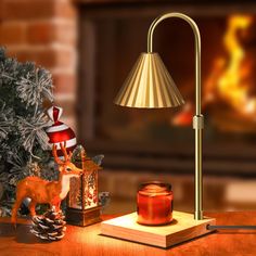 a table lamp sitting on top of a wooden table next to a candle and christmas tree