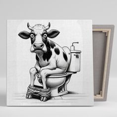 a black and white cow sitting on top of a toilet next to a wooden box