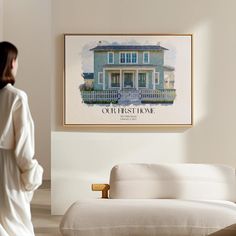 a woman standing in front of a white couch with a blue house on the wall