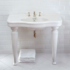 a white bathroom sink sitting next to a towel on top of a counter under a mirror