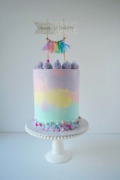 a multicolored cake on a white pedestal