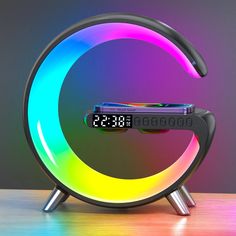 an alarm clock sitting on top of a wooden table next to a neon colored light