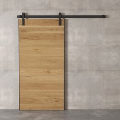 an empty room with a wooden door and black metal bars on the wall, in front of a concrete wall