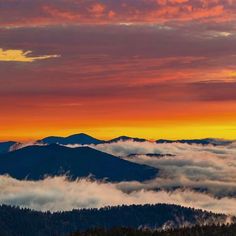 the sun is setting over some mountains covered in clouds