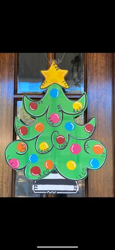 a green christmas tree shaped door hanger in front of a wooden door with a star on top