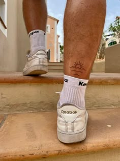 a man with his foot up on the steps wearing white sneakers and socks that say robabk