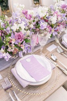 the table is set with purple and white flowers