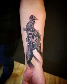 a person with a tattoo on their arm is riding a dirt bike and has a skull in the middle