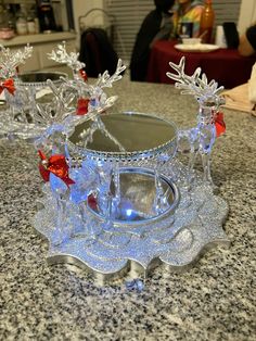 two glass sleighs with red bows and snowflakes on them sitting on a granite counter top