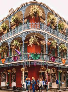 people standing in front of an ornate building with balconies and flowers on it