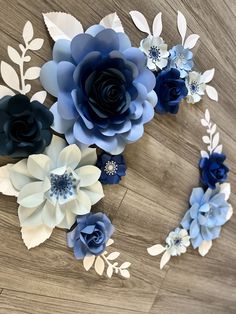 blue and white paper flowers are arranged on a wooden surface, with leaves in the center