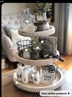 three tiered trays with plants and vases on top of each other in front of a couch