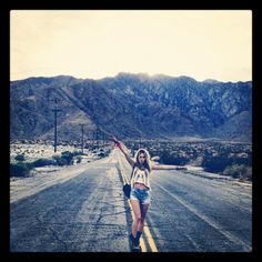 a woman is walking down the road with her arms in the air