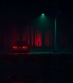 a car is parked in the dark under a street light with red lights on it