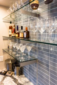 wine glasses are lined up on glass shelves