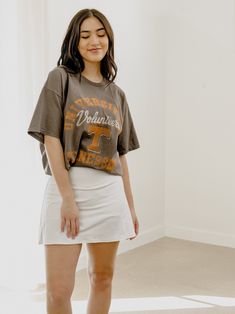 **Please allow 2 Weeks for Item to Ship** Our 100% Preshrunk Cotton thrifted tees are meaningfully distressed and officially licensed. Each piece is one of a kind, and colors/distressing may vary from shirt to shirt.Pairs well with vintage denim and your favorite kicks.The details:- 100% Preshrunk Cotton- Meaningfully Distressed, each piece unique- Colors + Distressing may vary- Officially Licensed Casual Distressed Top For Game Day, Sporty Distressed Tops For Spring, Collegiate Style Spring T-shirt With Graphic Print, Graphic Tee For Game Day In Spring, Distressed Crew Neck Tops For College, Spring Streetwear T-shirt With School Spirit Style, Distressed Cotton Top For Game Day, Spring Crew Neck T-shirt With School Spirit, Cotton Distressed Top For Game Day