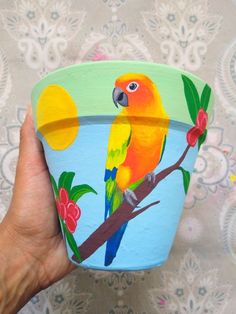 a hand holding a painted pot with a bird on it