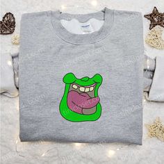 a gray shirt with an image of a green monster on it's chest and tongue