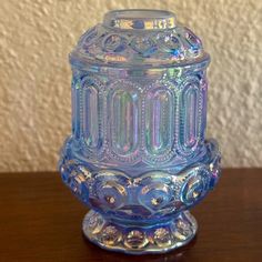 a blue glass jar sitting on top of a wooden table next to a white wall