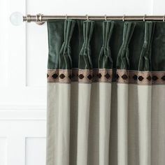 a curtain with green and brown trim hanging from a metal rod