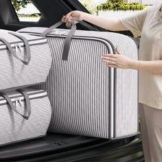 a woman holding two suitcases in the back of a car