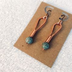 copper and turquoise stone earrings sitting on top of a piece of paper