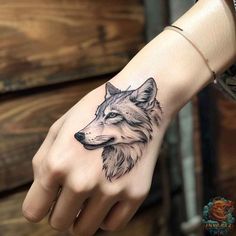 a hand with a wolf tattoo on it