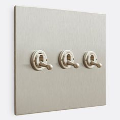 an image of three light switches on a metal wall mounted switch plate with two knobs