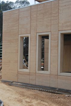 the side of a building with three windows and no doors on it, in front of a construction site