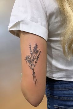 a woman with a tattoo on her arm holding a bouquet of wildflowers in her left arm