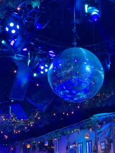 a large blue ball hanging from the ceiling in a room filled with lights and decorations