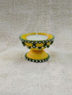 a yellow candle holder sitting on top of a white carpeted floor next to a wall