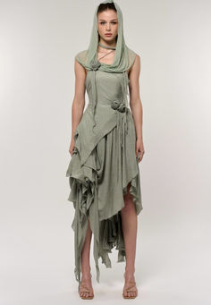 This set includes a sleeveless, fitted bodicean top and an asymmetrical skirt, featuring cascading ruffles in the same seafoam green ribbed fabric. The crisp and enchanting green, filled with vibrant vitality, evokes the sense of everything springing back to life and flourishing. These ruffles add volume and create a flowing, dynamic look as they unevenly descend to varying lengths around the skirt, with some layers reaching down to the ankle. Apocalyptic Fashion, Cascading Ruffles, Back To Life, Asymmetrical Skirt, Seafoam Green, Ribbed Fabric, Oasis, Ruffles, Sense