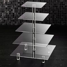 a three tiered glass display case on a table in front of a tiled wall