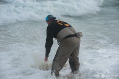 a man standing in the ocean with his feet in the water and holding onto something