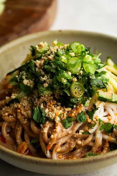 a close up of a bowl of food with noodles and vegetables in it on a table