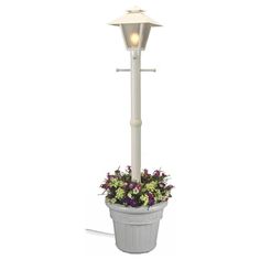 a white lamp post with flowers in it and a potted plant on the side