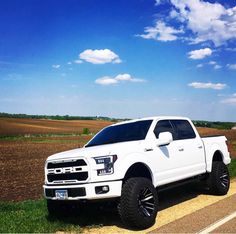 a white truck is parked on the side of the road in front of a plowed field