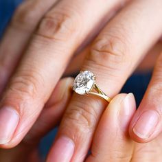 a woman's hand holding a ring with a diamond on it and the middle finger