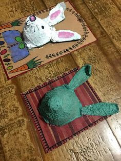 there are two paper mache animals on the table together, one is green and the other is pink