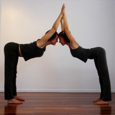 a man and woman doing yoga poses in an empty room with wood floors on the floor