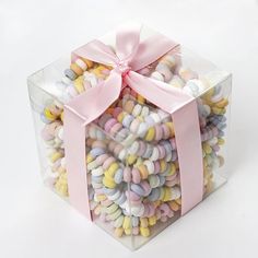 a clear box filled with lots of colorful candies and a pink ribbon tied around the top