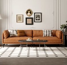 a living room with an orange couch and coffee table in front of white wall decor