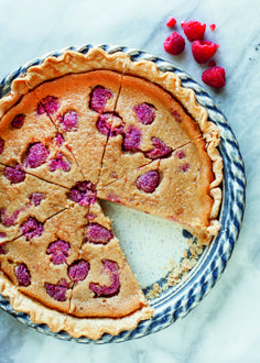 a pie with raspberries cut into slices on a plate