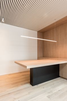 an empty room with wooden flooring and lighting above the table, in front of a white wall