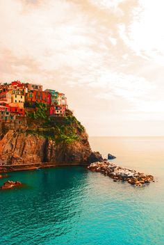 an island with houses on top of it in the middle of the ocean and blue water