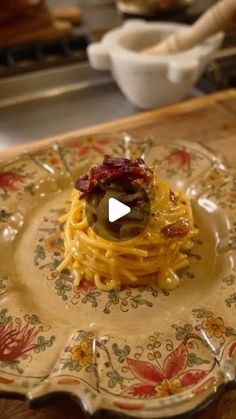 a plate with spaghetti and olives on it in front of a bowl full of other food