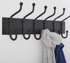 four black hooks hang on a white wall with clothes hanging from it's hooks