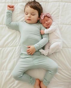 a baby sleeping on top of a bed next to an adult